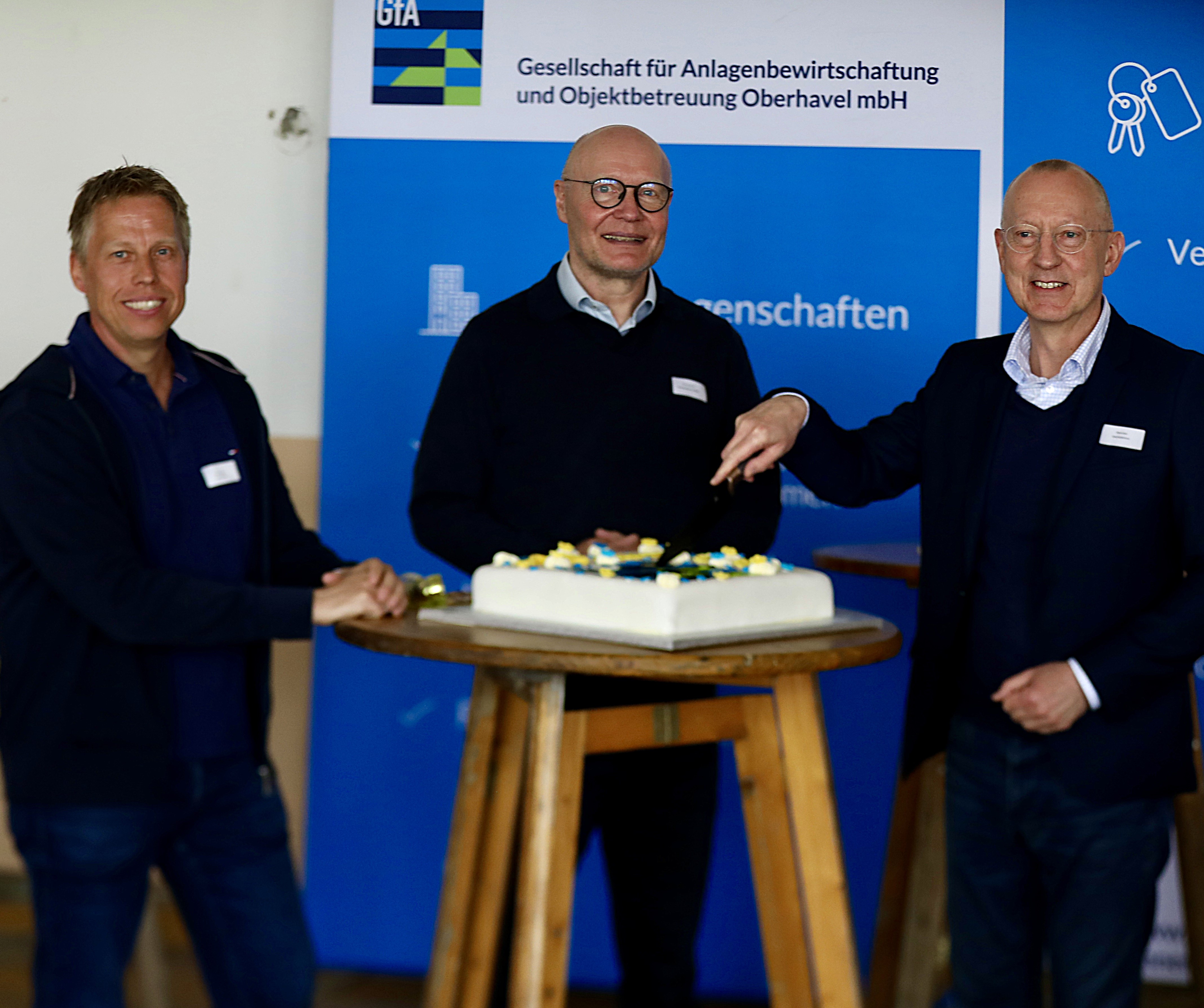 Markus Meyer, Andreas Ernst, René Kohl (v.li.n.re.) schneiden die Geburtstagstorte an.
